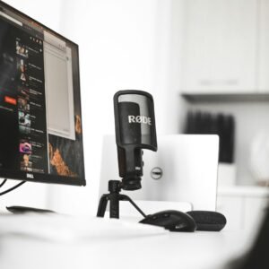 black Rode condenser microphone beside computer monitor